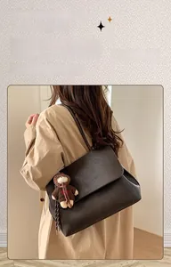 Dettaglio borsa tote in pelle marrone scuro con ciondolo a forma di orsetto per inverno