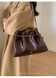 Detail der dunkelbraunen Steppledertasche mit goldenem Logo und Kordelzugverschluss