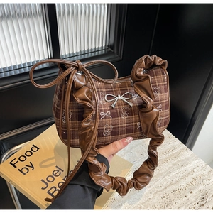 Detail of brown plaid texture with bear print and silver bow charm on stylish handbag