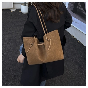 Detail shot of a brown suede tote bag with stylish knot strap detail on a model