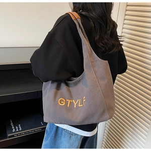 Detailed view of grey canvas tote bag with GTYLF embroidery and brown leather handles