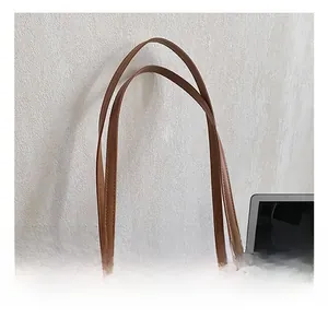 Detail of brown litchi pattern tote bag featuring durable handles and metal ring accents