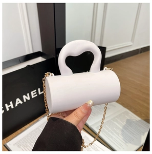 Détail du mini sac cylindrique blanc avec poignée en cœur et chaîne dorée élégante