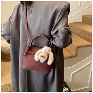 Detail of burgundy bucket bag with HOGOMU logo and cute plush rabbit charm accessory