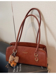 Bolso retro de piel sintética marrón con amuleto de oso sobre un libro de diseño