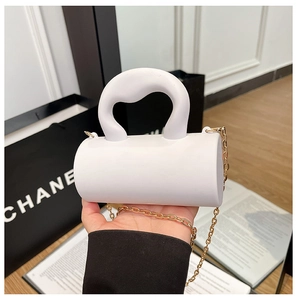 Détail du mini sac cylindre blanc avec poignée ondulée et chaîne dorée