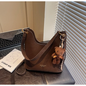 Detail der braunen Hobo-Tasche mit goldenen Beschlägen und Plüschbär-Anhänger