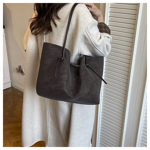 Brown large tote bag with knotted strap details shown on model in a beige coat