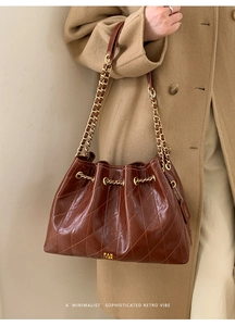 Detailansicht der braun gesteppten Eimer-Tasche aus Ölwachsleder mit Goldkette