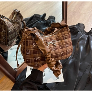 Detail of checkered canvas bag with bear prints and a pleated leather handle in mirror view
