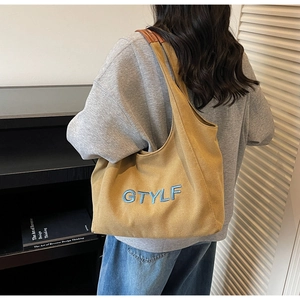 Detail of canvas tote with blue GTYLF embroidery and brown leather trim accents