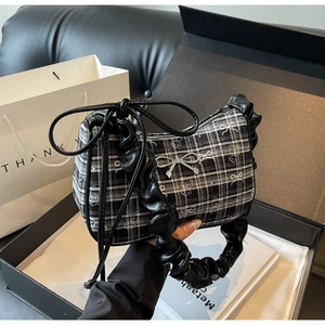 Detail of checkered shoulder bag with silver bow accessory and ruched leather handle