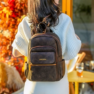 Detailed back view of a woman wearing a dark vintage matte backpack in an autumn setting