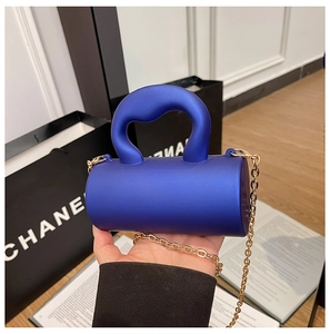 Détail du sac cylindrique en acrylique bleu roi avec poignée épaisse et chaîne dorée