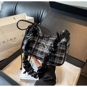 Detail of black and white checkered underarm bag with ruffled edges in a gift box