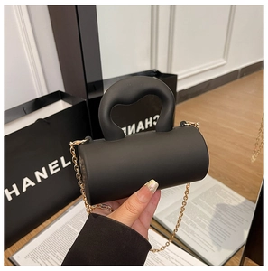 Détail du mini sac à main cylindrique en acrylique noir mat avec chaîne dorée