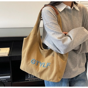 Detail shot of khaki canvas tote with blue GTYLF embroidery and brown shoulder strap