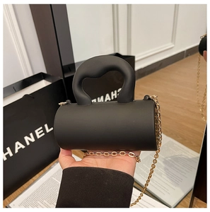Détail du sac cylindrique noir mat avec poignée en forme de vague et chaîne dorée