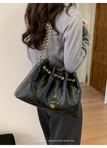 Details der schwarzen gesteppten Beuteltasche mit PAN TOR Goldschrift und Kettenriemen