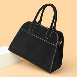 Close-up of black matte tote bag with white contrast stitching and gold hardware detail