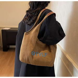 Close-up of blue GTYLF embroidery on brown canvas tote bag with leather strap