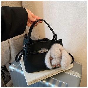 Detail of black pebbled leather bucket bag with silver turn-lock and cute bunny charm