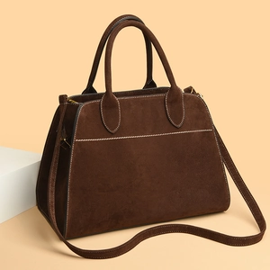 Detail view of dark brown suede tote bag featuring white stitching and smooth handles