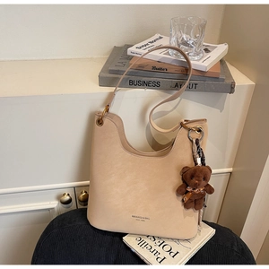 Detailansicht der beigen matten Ledertasche mit einem süßen braunen Plüschbären
