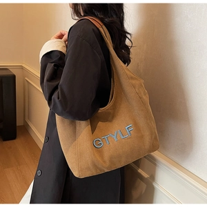 Detailed close-up of brown corduroy tote bag featuring blue GTYLF letter embroidery