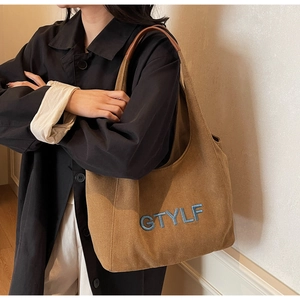 Detailed close-up of GTYLF letter embroidery on a vintage brown canvas tote bag
