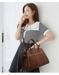 Brown suede tote bag detail featuring cylindrical handles and adjustable side buckles