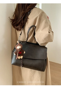 Dettaglio borsa shopper retrò marrone scuro con ciondolo a orsetto su trench kaki