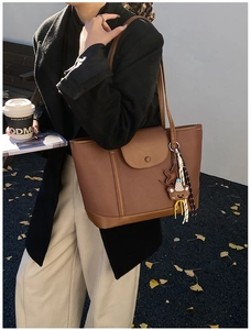 Brown lychee leather tote bag featuring magnetic flap and cute bear pendant on a model