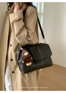 Dettaglio di una grande borsa a spalla in pelle nera opaca con ciondolo a forma di orsetto