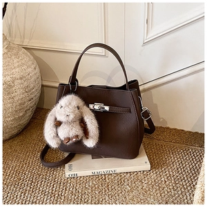 Detail of coffee brown bucket bag with lychee texture and cute plush bunny charm