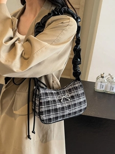 Black and white checkered underarm bag with ruffled strap and metal bow detail