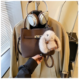Detail of brown litchi pattern bucket bag with silver lock and plush bunny pendant