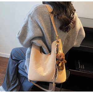 Detailansicht einer aprikosenfarbenen Ledertasche mit einem kleinen Plüschbären-Anhänger