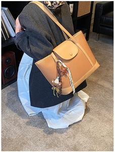 Close-up of caramel leather tote bag with lychee texture and cute bear star charms