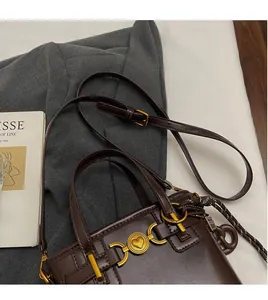 Detail of adjustable long shoulder strap and golden heart buckle on dark brown bucket bag