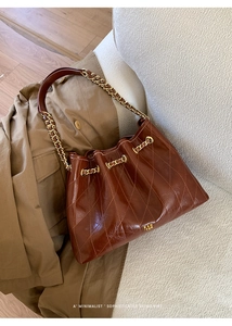Detail der dunkelbraunen gesteppten Ledertasche mit goldener Kette und Kordelzug