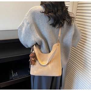 Detail view of khaki hobo shoulder bag in soft suede texture with a cute brown bear charm