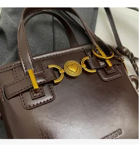 Close-up of brown textured leather handbag with golden heart-embossed hardware