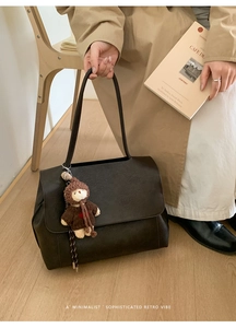 Dettaglio borsa tote vintage marrone scuro con ciondolo a orsetto e chiusura a patta