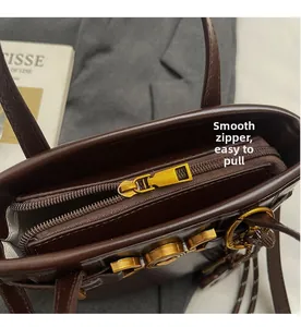 Detail of smooth bronze metal zipper closure on a premium dark brown leather bucket bag