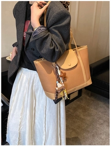 Detailed view of light brown pebbled leather tote bag with cute plush bear charms