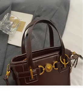 Close-up of vintage brown leather bucket bag with gold heart hardware and shoulder strap