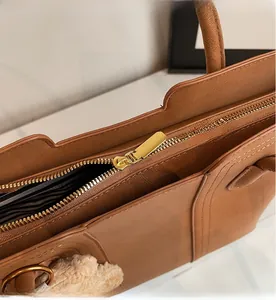 Dettaglio della cerniera dorata su una borsa tote marrone con fodera in tessuto a righe