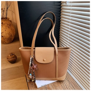 Detail of brown litchi pattern tote bag with flap snap closure and star charm