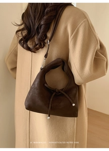 Detail showing deep brown leather shoulder bag with knot design and silver metal hardware